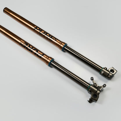 Two metal suspension forks on a gray background